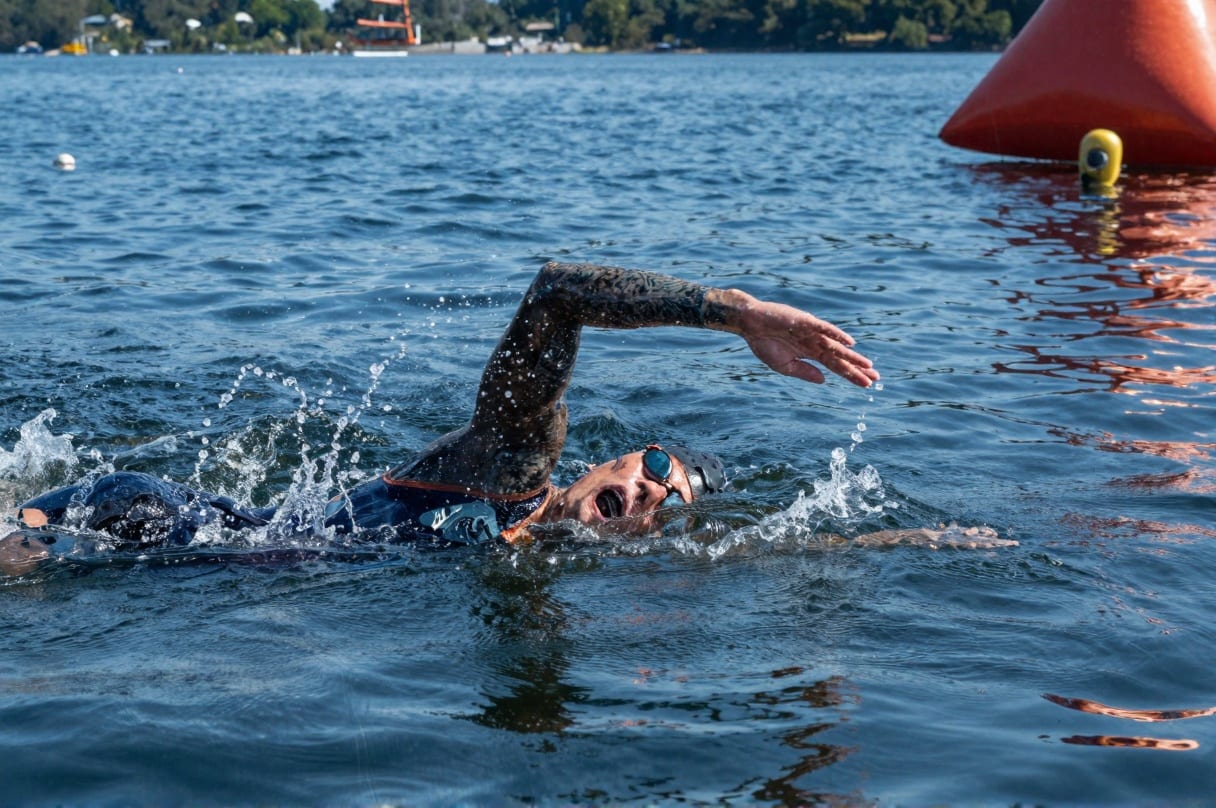 Open water swimming with orange marker buoys